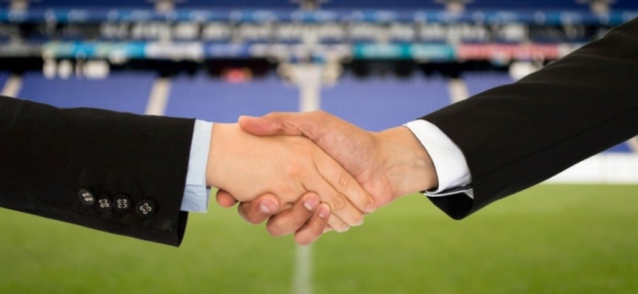 Handshake with football field in background Handshake with football field in background