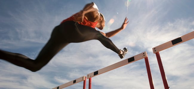 Athlete jumping over hurdle on track