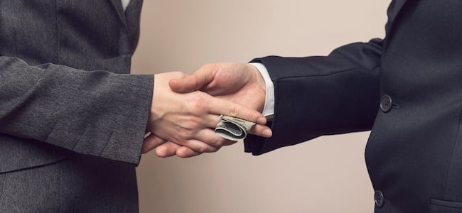 Bribe being expected with a handshake