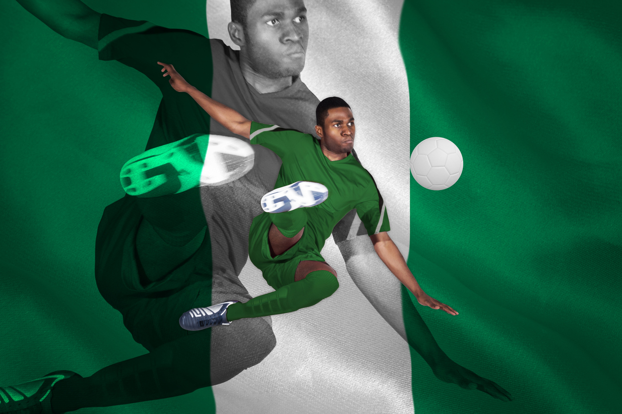 Player kicking soccer ball with Nigerian flag in background