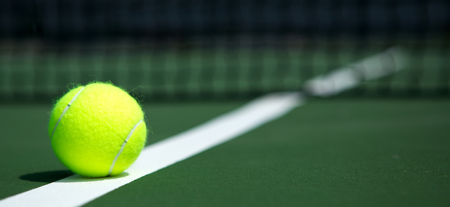 Tennis ball resting on tennis court